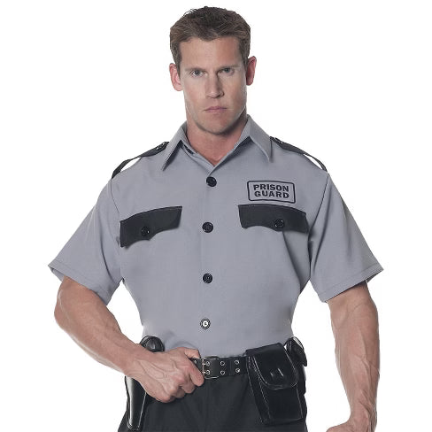 A man in a prison guard costume wearing a light blue shirt with black tie, black pants, and official-looking patches on the sleeves, designed to resemble a corrections officer or security personnel