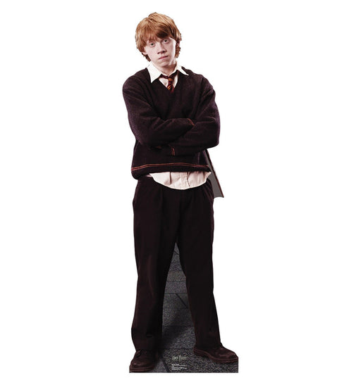 A young man with red hair wearing a dark brown sweater, white shirt, red and gold striped tie, and dark pants.