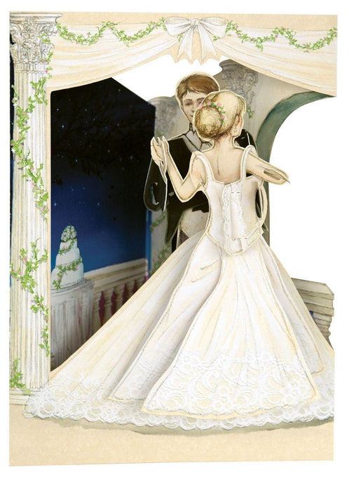 A romantic cutout illustration of a bride in a flowing white wedding gown dancing with a groom in a black tuxedo beneath an ivy-draped archway, with a tiered cake and starry night sky in the background.