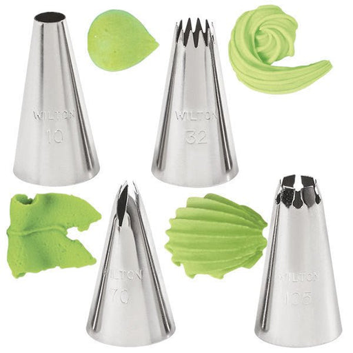 Set of five stainless steel Wilton piping tips, each producing different green frosting designs, including smooth leaf shapes, ridged swirls, ruffled edges, and textured patterns.
