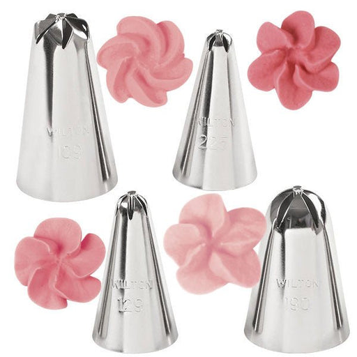 Set of five stainless steel Wilton piping tips, each creating unique pink frosting flower designs, including swirled petals, rounded blossoms, and multi-pointed floral patterns.