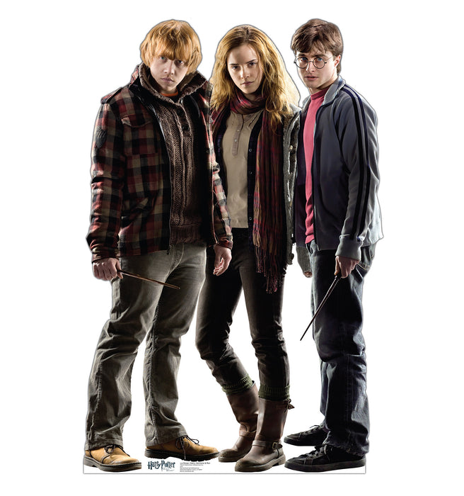 A life-size cutout of three young characters standing together: a red-haired boy in a plaid jacket, a girl with wavy hair in a scarf and boots, and a dark-haired boy in glasses holding a wand.