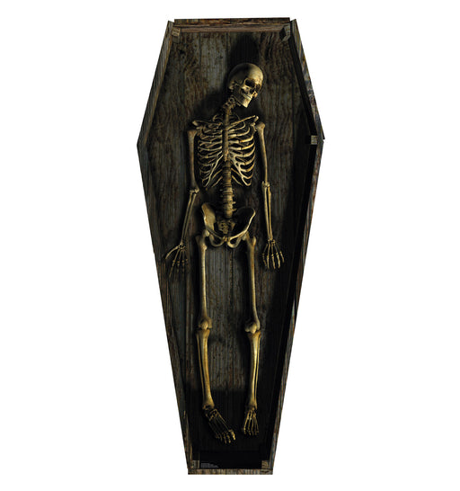 Life-size cardboard cutout of a human skeleton lying in a dark, weathered wooden coffin with a slightly tilted head and relaxed limbs.