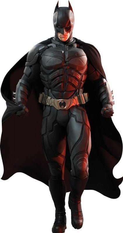 Life-size cardboard cutout of a muscular superhero dressed in a detailed black armored Batsuit with a gold utility belt, black gloves, boots, and a flowing black cape. He wears a cowl with pointed ears and strides forward with a serious expression.