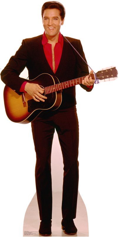 Life-size cardboard cutout of a smiling man with slicked-back hair wearing a black suit with a red shirt, holding an acoustic guitar as if mid-performance.