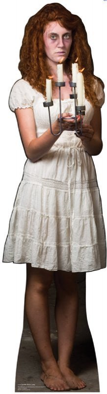 Life-size cardboard cutout of a pale, ghostly woman with long red hair wearing a short white dress. She stands barefoot and holds a candelabra with three lit candles, gazing forward with a haunting expression.