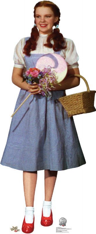 Young girl with fair skin and auburn pigtails, wearing a white puff-sleeved blouse and a light blue gingham pinafore dress. She holds a pastel pink and purple swirled lollipop and a small bouquet of pink and purple flowers. A light brown wicker basket hangs from her left arm. She wears white socks and sparkling ruby red shoes.
