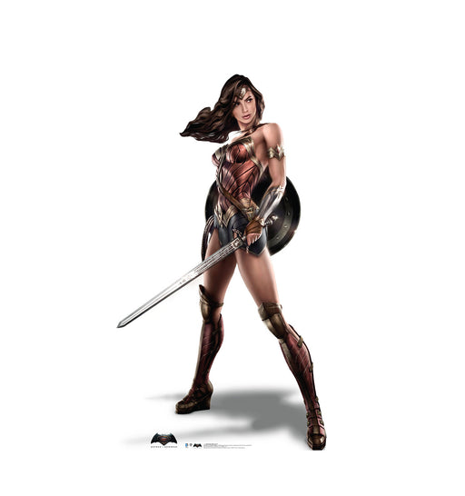 Cut-out of Wonder Woman, the comic book superhero, standing in a powerful stance holding a sword in her right hand and a shield strapped to her left arm. She is wearing her iconic red and gold armor with blue skirt, knee-high armored boots, and a tiara, with her hair flowing to the side.