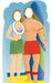 Colorful cartoon-style cardboard cutout of a Hawaiian couple standing on a beach. The woman wears a green grass skirt, purple top, white lei, and has a purple flower in her brown hair. The shirtless man wears red shorts and red ankle garlands, holding a large blue and green striped surfboard. Both have blank oval faces for photo opportunities.