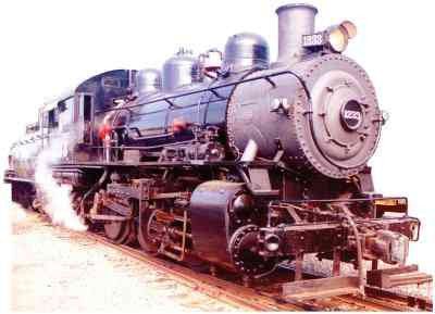 A large black steam locomotive marked with the number '1880' on the front, featuring a rounded smokebox, headlamp, and various steam components, emitting steam from the side as it sits on railroad tracks.