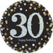 Black round plate with a large light blue glittery number '30' in the center, surrounded by gold, silver, and white confetti dots, with the words 'happy birthday' in lowercase script below the number.