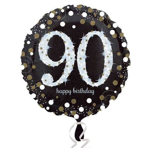Round black foil balloon with large silver glitter-effect number '90' in the center, surrounded by gold and silver confetti dots, and the words 'happy birthday' in small white script below.