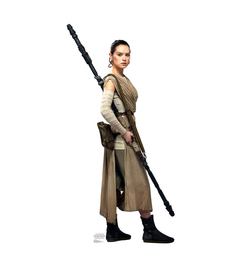 Cutout standee of Rey from Star Wars, wearing her scavenger outfit in shades of beige and brown, holding her staff diagonally across her body.