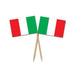 Pair of food picks featuring miniature Italian flags with vertical stripes in green, white, and red. The flags are attached to wooden toothpick-style sticks and arranged in a crisscross pattern.