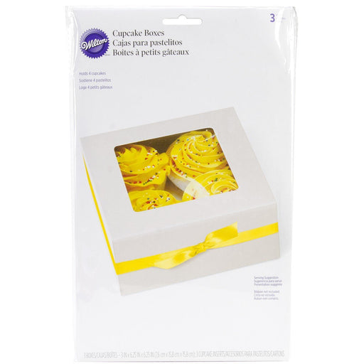 Package of Wilton cupcake boxes designed to hold four cupcakes each, featuring a white box with a clear window on top and a decorative yellow ribbon, shown with yellow frosted cupcakes inside.