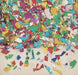 Pile of colorful metallic confetti pieces scattered on a surface, featuring irregular shapes in reflective red, blue, green, yellow, silver, pink, and purple colors.