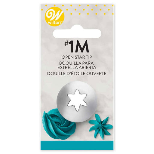 Wilton #1M open star piping tip in retail packaging, featuring a metal tip with a large open star-shaped cutout. The white card backing displays the Wilton logo, product name in English, Spanish, and French, and examples of teal icing swirls and rosettes at the bottom.