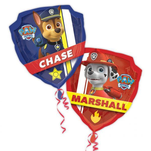 A pair of Paw Patrol-themed foil balloons shaped like shields, featuring Chase the police pup on a blue shield with a yellow star and Marshall the firefighter pup on a red shield with a flame icon, each with red curling ribbons attached.