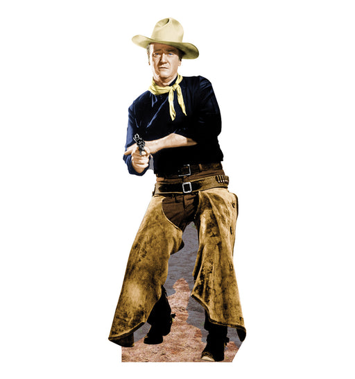 Life-size cutout of a cowboy wearing a beige hat, dark blue shirt, yellow neckerchief, brown leather chaps over dark pants, and black boots. He is holding a revolver in both hands, poised in a defensive stance. The base shows a dusty western ground.