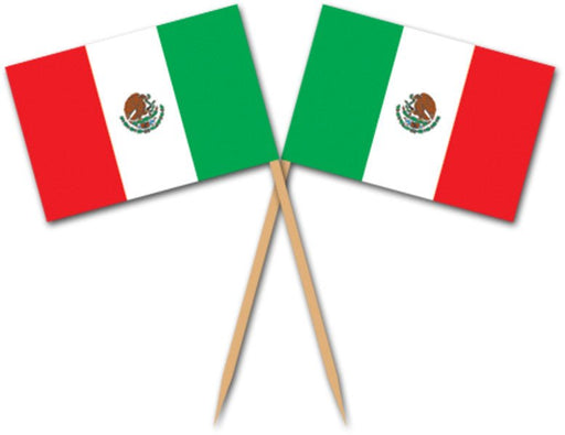 Pair of food picks featuring miniature Mexican flags with vertical stripes in green, white, and red, and the national coat of arms in the center. The flags are attached to wooden toothpick-style sticks and arranged in a crisscross pattern.