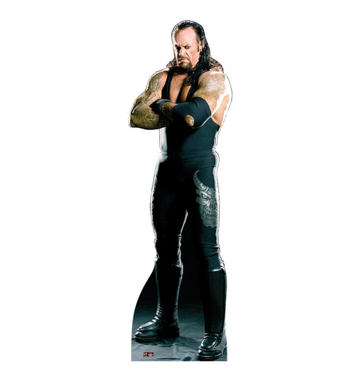 Life-size cardboard cutout of a muscular man with long hair and tattoos, dressed in a black tank top, black pants, and black boots, standing with arms crossed and an intense expression.