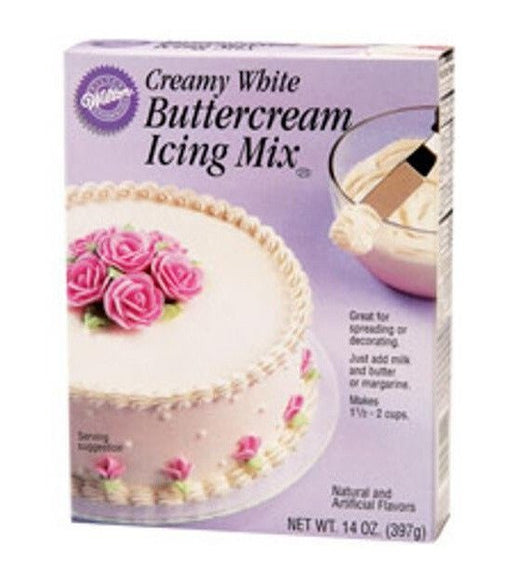 Box of Wilton Creamy White Buttercream Icing Mix with light purple packaging, showing a white frosted cake decorated with pink rose flowers, and a mixing bowl with a spatula.
