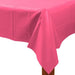 Rectangular table covered with a bright pink plastic tablecloth, draped smoothly over the corners, with part of a wooden table leg visible underneath.