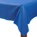 Blue rectangular plastic table cover draped over a wooden table corner, with visible folds and a glossy finish.