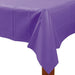 Purple rectangular plastic table cover draped over a wooden table, with slight creases and a glossy finish.