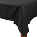 Black rectangular tablecloth draped over a wooden table, with neatly hanging corners and slight creases along the surface.