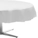 Round table covered with a plain silver plastic tablecloth, draping over the edges and partially concealing a silver metal base.