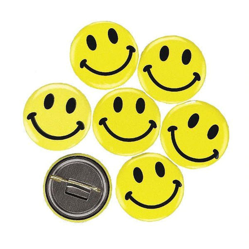 Seven round yellow buttons with black smiley face designs arranged on a white background. One button is flipped to show the silver metal pin backing with a safety clasp.