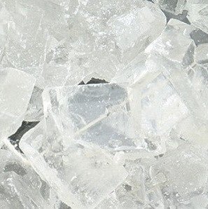 Close-up view of clear rock candy crystals showing sharp, angular sugar facets with a translucent, glass-like appearance.