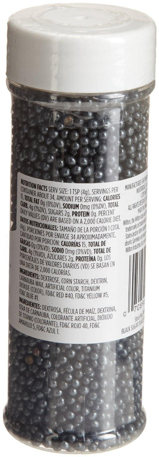 A clear plastic container filled with small, round black sugar pearls used for decorating baked goods. The container has a white lid and a label displaying nutrition facts and ingredient information.