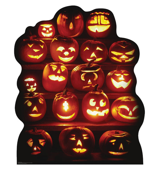 A group of glowing orange jack-o'-lanterns stacked in rows, each carved with a different expressive face, lit from within against a dark background.
