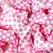 Close-up of numerous pink and white polka-dotted candy wrappers scattered in a pile.