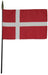 Rectangular flag with a red background and a white Scandinavian-style cross that extends to all edges. The vertical part of the cross is shifted toward the hoist side. The flag is mounted on a black pole with a dark gold spear-shaped tip.