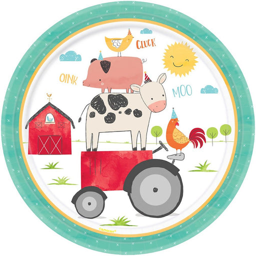 Round paper plate with a farm animal party design. The illustration shows a cow standing on a red tractor, with a pig on its back and a chicken on top, all wearing party hats. A rooster, barn, sun, and text 'OINK,' 'CLUCK,' and 'MOO' complete the scene.