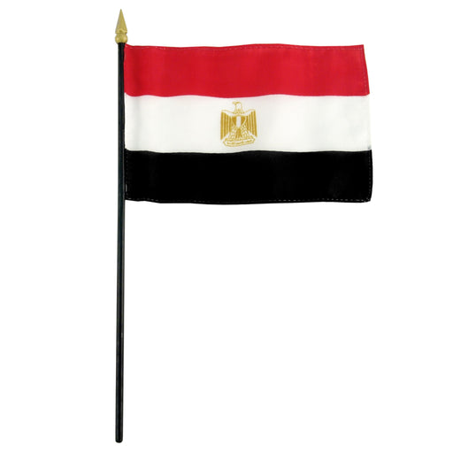 Rectangular flag with three horizontal stripes: red at the top, white in the middle, and black at the bottom. A gold emblem is centered in the white stripe. The flag is mounted on a black pole with a gold spear-shaped tip.