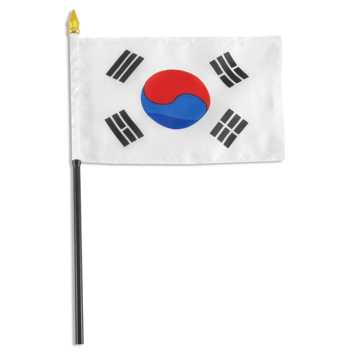 Rectangular white flag featuring a red and blue circular symbol in the center. Surrounding the circle are four black trigrams, each consisting of three lines in different arrangements, positioned in each corner. The flag is mounted on a black pole with a white sleeve and a gold spear-shaped tip.