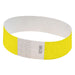 Bright yellow Tyvek wristband with white adhesive area and black numbering.